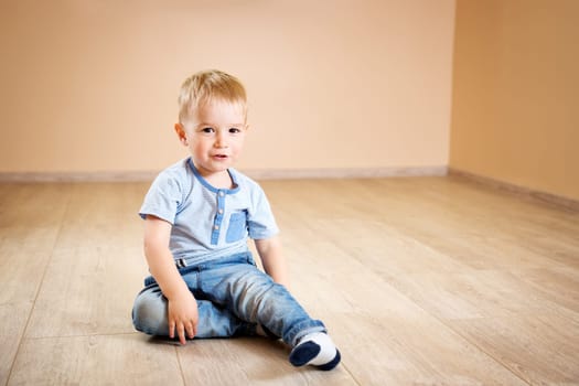 Portrait of a two years old child sitting on the floor. Pretty little boy at home
