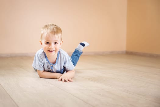 Portrait of a two years old child lying on the floor. Pretty little boy at home