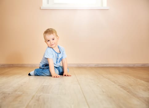 Portrait of a two years old child sitting on the floor. Pretty little boy at home