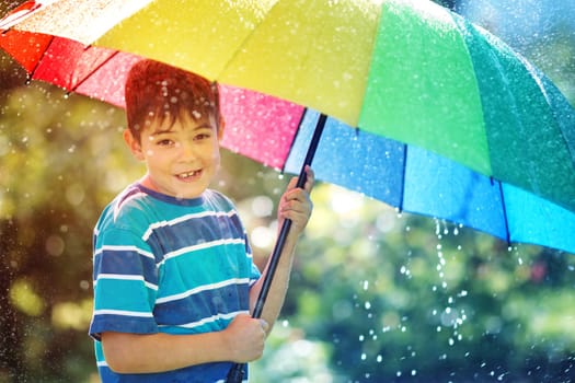 Child on rainy weather. Boy holding colourful umbrella under rain in summer