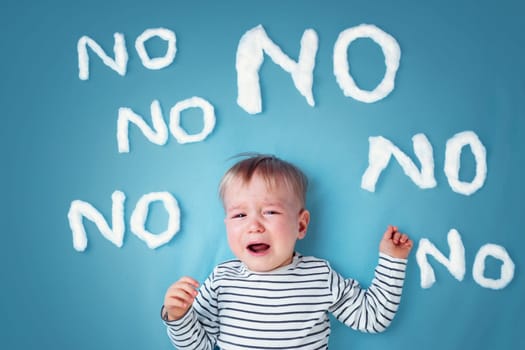 sad boy on blue blanket background. Unhappy child with no words around