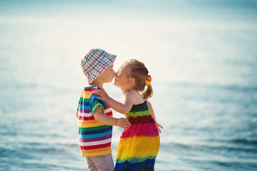 Babygirl and babyboy kissing on the beach at sea