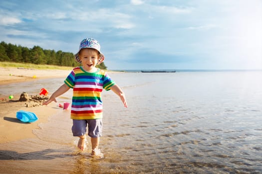 Baby boy playing with ship toy at sea. Child os on vacation in summer at the beach on vacations