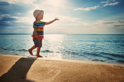 Baby boy playing with ship toy at sea. Child os on vacation in summer at the beach on vacations