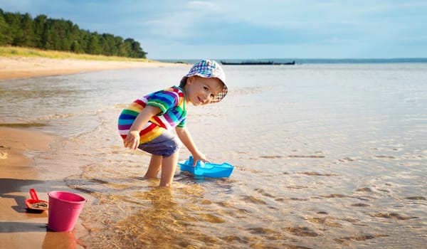Baby boy playing with ship toy at sea. Child os on vacation in summer at the beach on vacations
