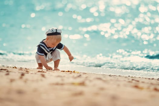 one year old boy walking at the beach in straw hat. Child on family vacations at sea