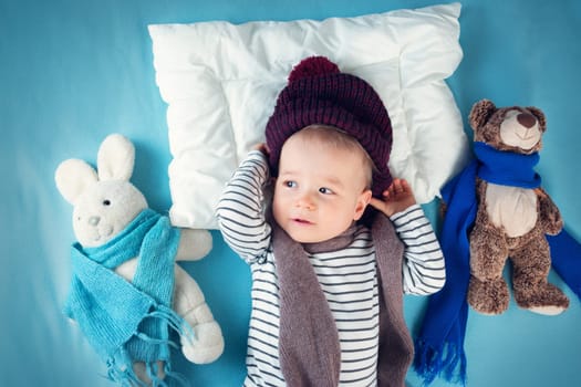 Ill boy lying in bed. cute child with fever and hat on head
