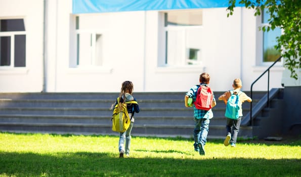 Children with rucksacks running in the park near school. Pupils with books and backpacks outdoors