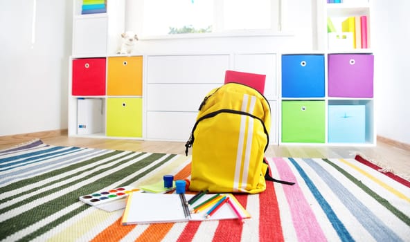 Colourful children rooom with white walls and furniture. Rainbow carpet at home interior with a window