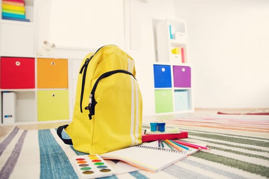 Colourful children rooom with white walls and furniture. Rainbow carpet at home interior with a window