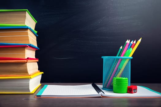 school accessories on the table with blackboard background. Pencils and books