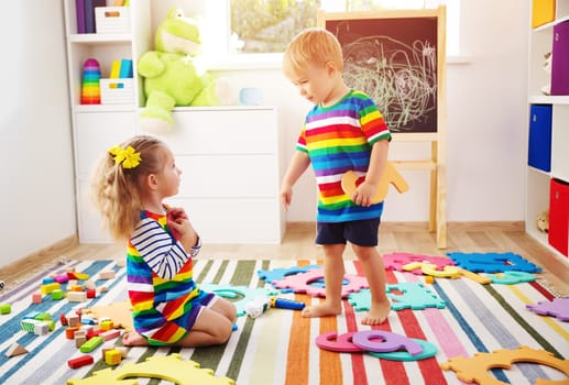 Little child playing with numbers. Boy and girl sitting on the floor at home