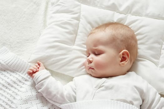 little boy sleeping on soft white blanket. 7 month old baby asleep