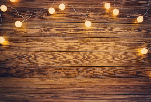 Old wooden planks with christmas decoration. Brown background with lightbulbs