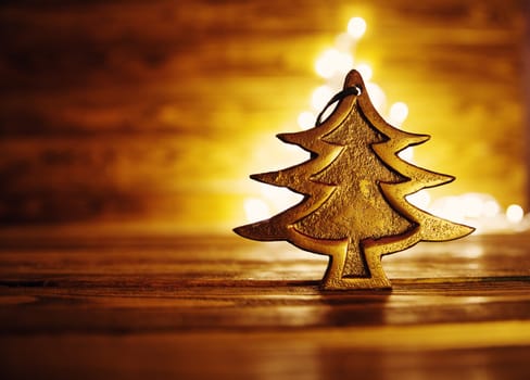 Fir tree toy on wooden background with christmas lights.
