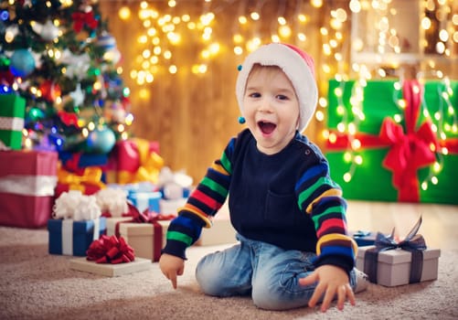 Boy and sitting on the floor with presents near christmas tree. Child in red hat at home in winter