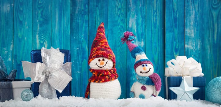 little knitted snowmans on soft snow on blue background
