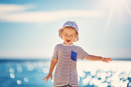 happy boy smiling at the beach in hat. Child on vacations at sea