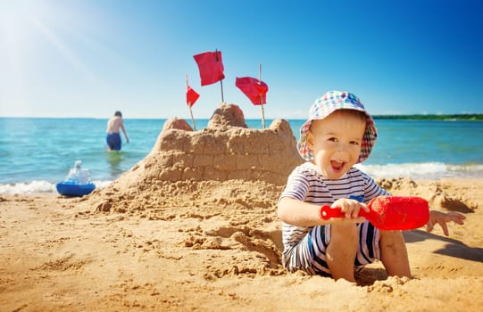 boy sitting smiling at the beach. Child on vacations at sea