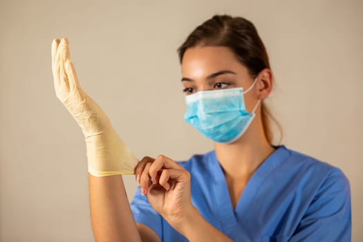 Young female nurse with blue surgical mask wearing protective rubber gloves. Concept of healthcare during pandemic of coronavirus. Doctor with protective equipment on hand.