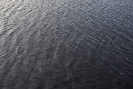 2 - Full frame gently rippled lake water. smooth sunlight gives gradual colors across the frame. Waves not cresting, evening daytime sunlight.