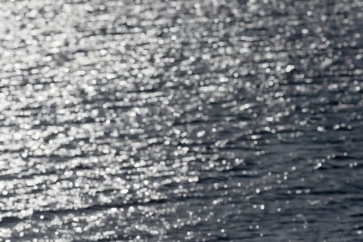 6 - Out of focus sunny water forms a pleasing smooth abstract background of lens effect bokeh. Water lake theme, outdoors image, into the sun.