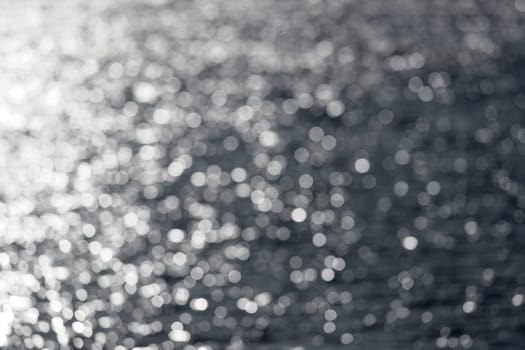 7 - Extra large white circular bokeh, formed by looking into the sun hitting water ripples on an outdoor reservoir lake. Abstract plain background.