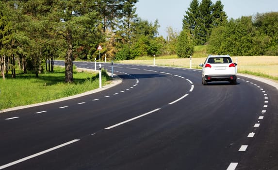 Car on black asphalt road in beautiful spring day at countryside