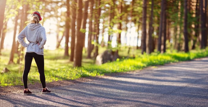 Young woman running on the field near seaside at sunset. Active person outdoors at the dusk in summer