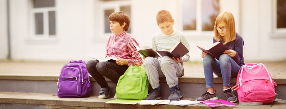 Children with rucksacks standing in the park near school. Pupils with books and backpacks outdoors