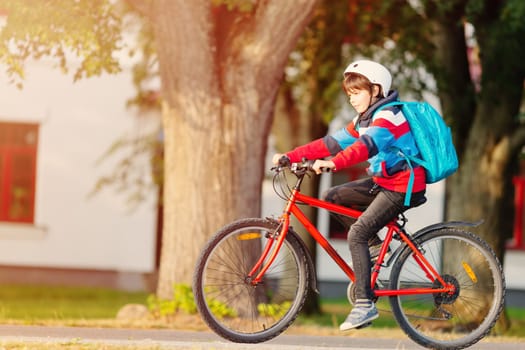Child with rucksack riding on bikes in the park near school. Pupil with backpack outdoors