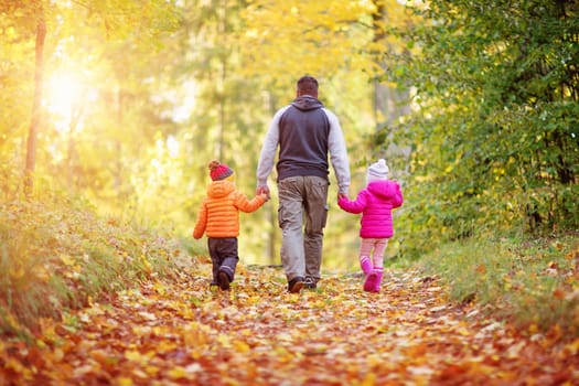boy and girl with father holding hands on the nature. Children with parent outdoors