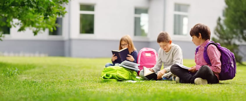 Children with rucksacks standing in the park near school. Pupils with books and backpacks outdoors