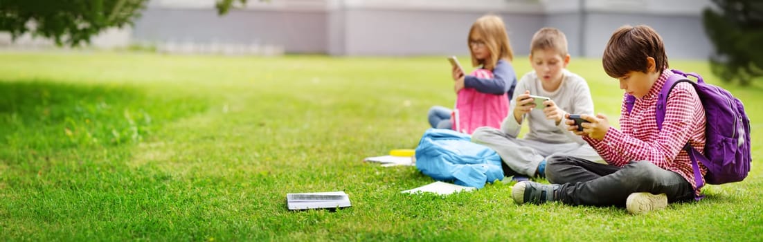 Children with rucksacks standing in the park near school. Pupils with books and backpacks outdoors