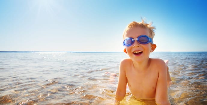 four years old boy playing at the beach with swimming glasses. Child on family vacations at sea