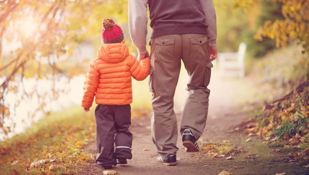Father and son having fun in beautiful autumnal day. Child playing outdoors in the park with man in autumn