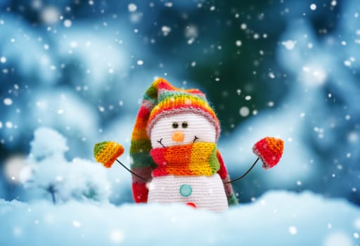 little knitted snowman on soft snow on blue background