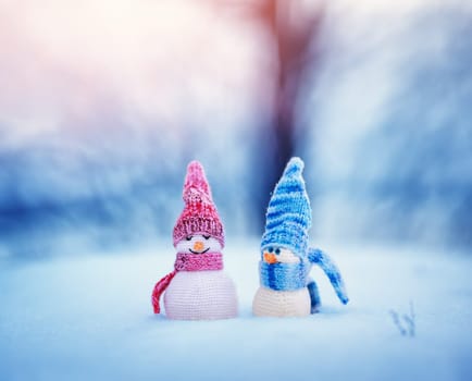 little knitted snowmans on soft snow on blue background