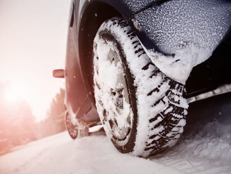 Car tires on winter road covered with snow. Vehicle on snowy way in the morning at snowfall
