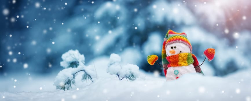 little knitted snowman on soft snow on blue background