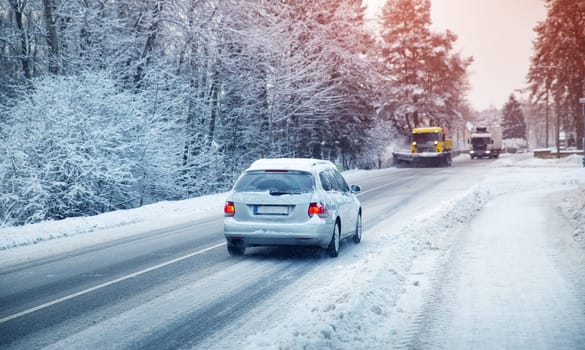 Car tires on winter road covered with snow. Vehicle on snowy alley in the morning at snowfall