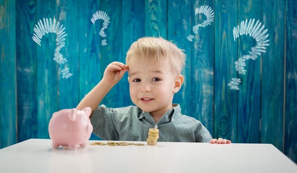 three years old child sitting st the table with money and piggybank. Happy boy with euro coins. Future childhood and education investment. Finance and savings concept