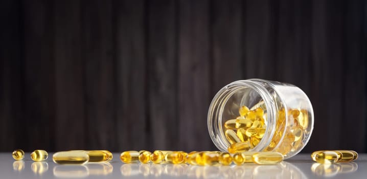 Pills in a jar on wooden background. D vitamin capsules with fish oil in a bottle