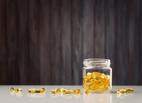 Pills in a jar on wooden background. D vitamin capsules with fish oil in a bottle