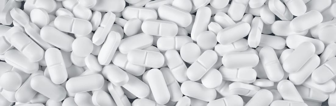 Pills spilled on blue background. A lot of white tablets