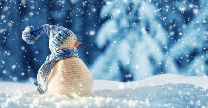little knitted snowman on soft snow on blue background