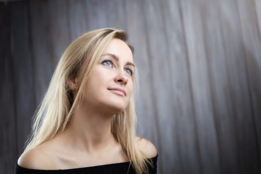 Happy beautiful young blond woman portrait with wooden background. Attractive girl in studio with long hair