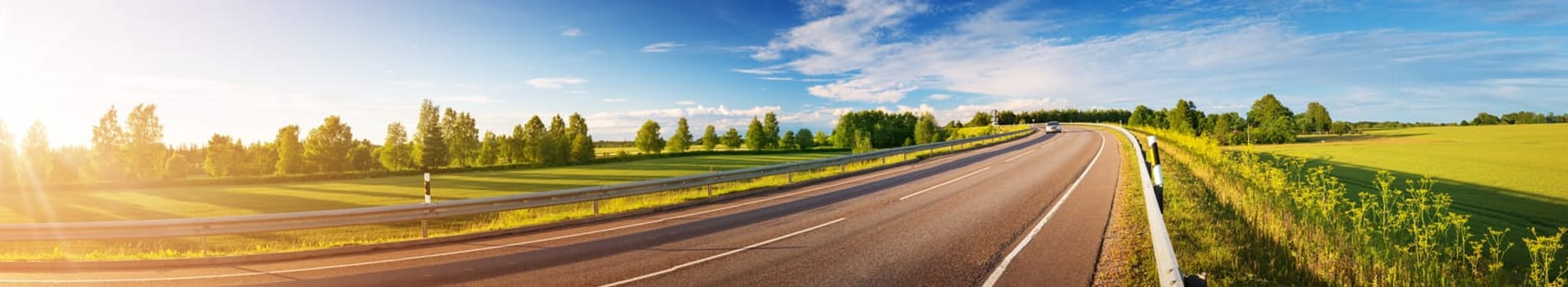 asphalt road panorama in countryside on sunny summer day. Empty highway landscape outdoors in nature with green grass and blue sky