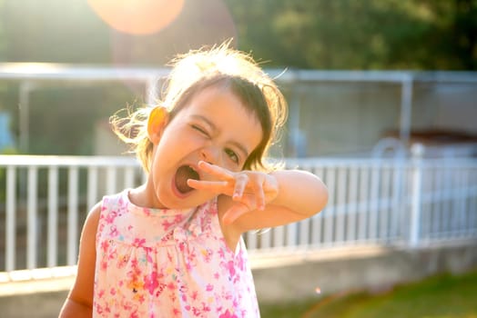 Sweet young girl making faces outdoors at sunset