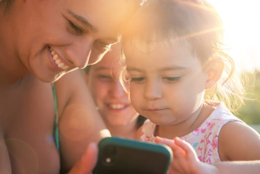 Girls looking at a phone outdoors at sunset